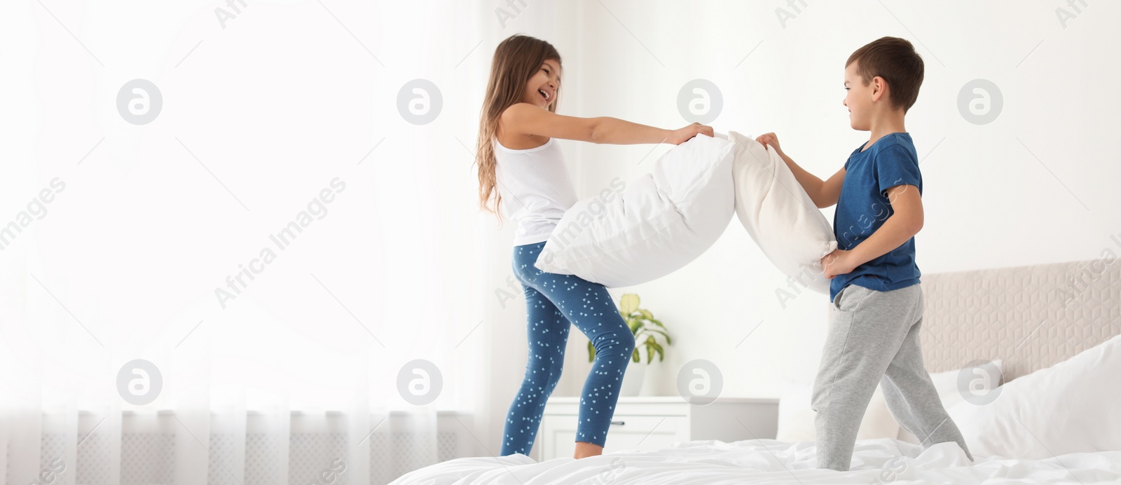 Image of Happy children having pillow fight in bedroom, space for text. Banner design