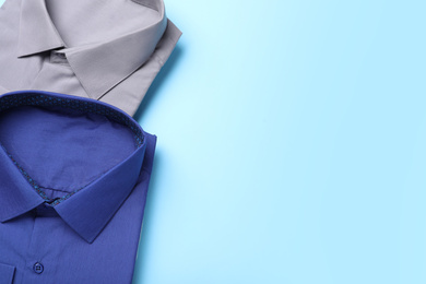 Stylish shirts on light blue background, flat lay with space for text. Dry-cleaning service