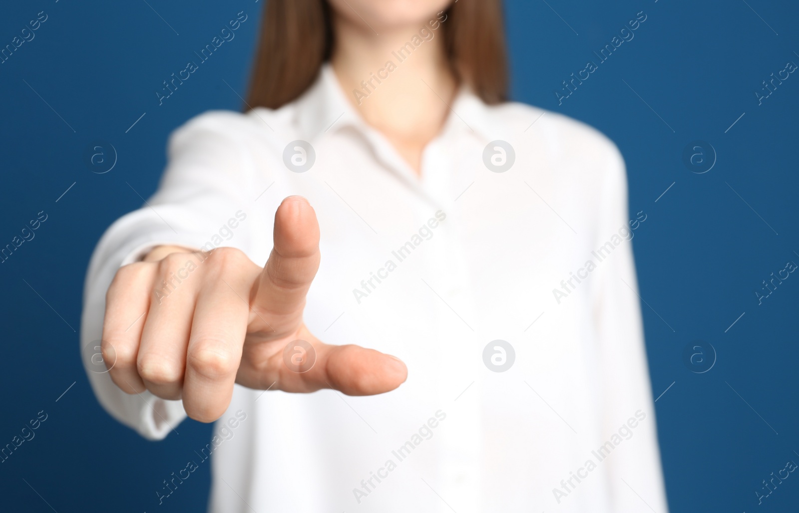 Photo of Young woman against blue background, focus on hand