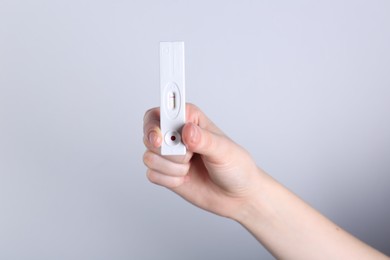 Photo of Woman holding disposable express test on light background, closeup