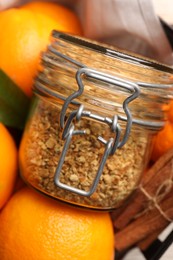 Photo of Jar of dried orange zest seasoning and cinnamon on fresh fruits, closeup