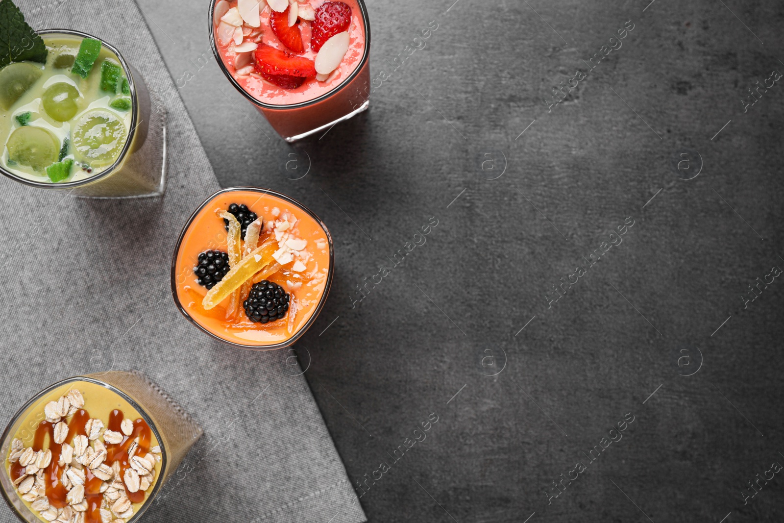 Photo of Many different delicious smoothies on grey table, flat lay. Space for text