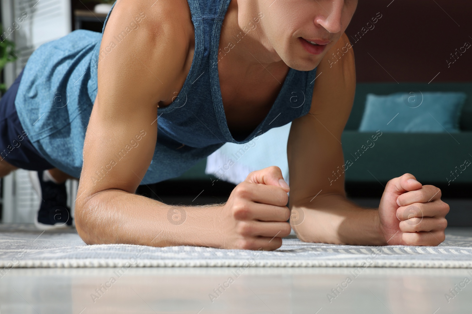 Photo of Man doing plank exercise on floor at home, closeup