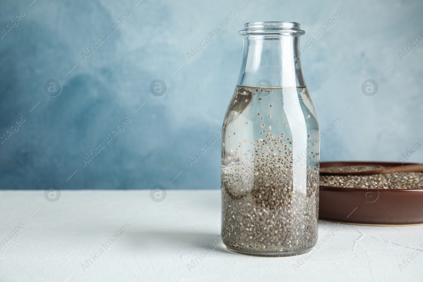 Photo of Composition with bottle of water and chia seeds on table against color background, space for text