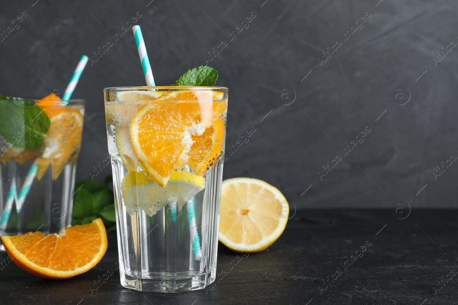 Photo of Delicious orange lemonade with soda water and mint on black table, space for text. Fresh summer cocktail