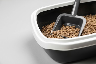 Photo of Cat litter tray with filler and scoop on light background, closeup