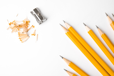 Photo of Graphite pencils, shavings and sharpener on white background, top view