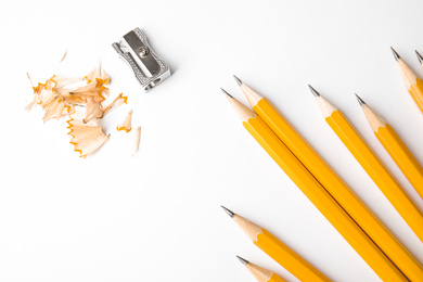 Graphite pencils, shavings and sharpener on white background, top view