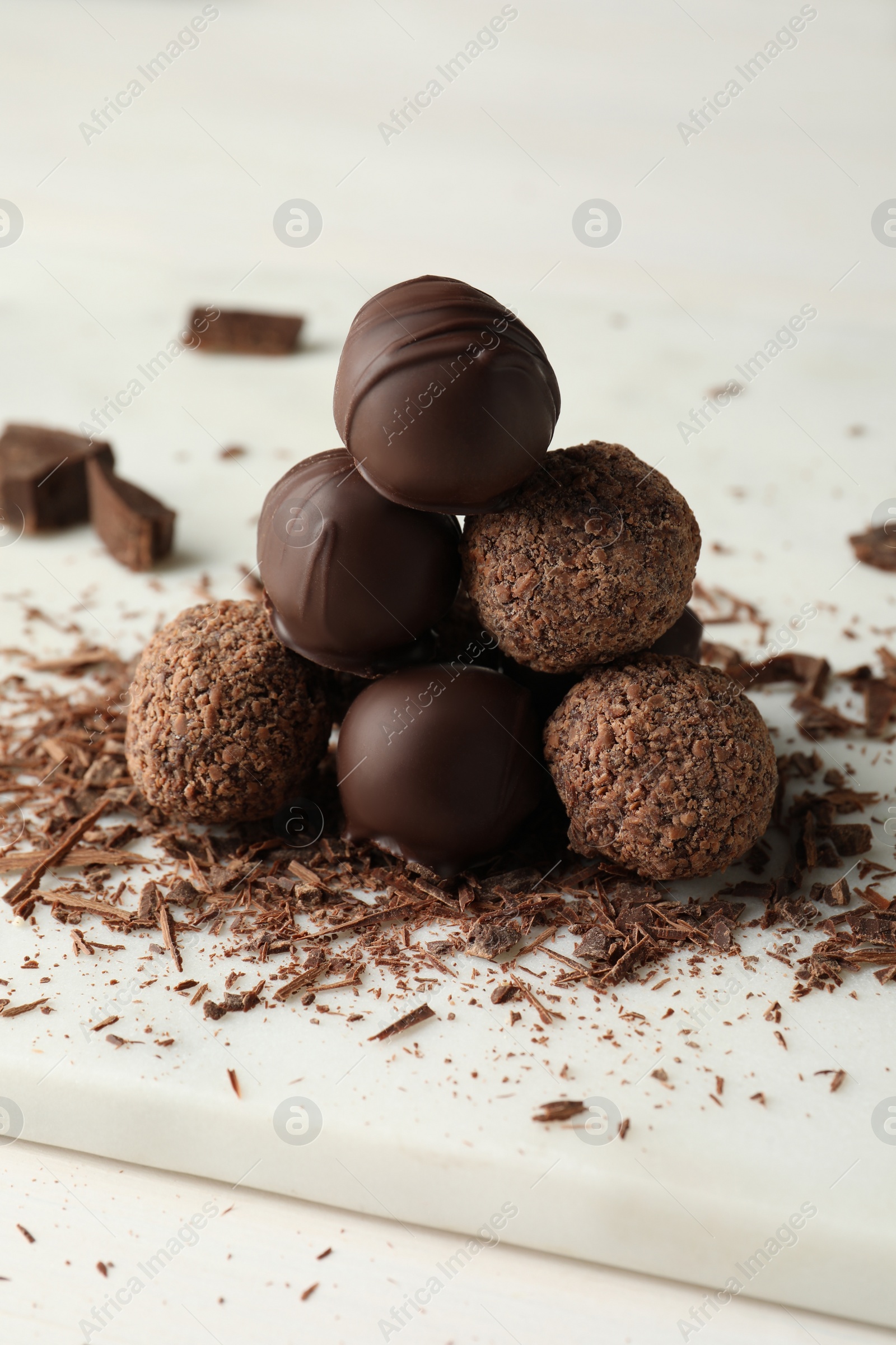 Photo of Many delicious chocolate truffles on white board, closeup