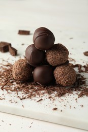 Many delicious chocolate truffles on white board, closeup