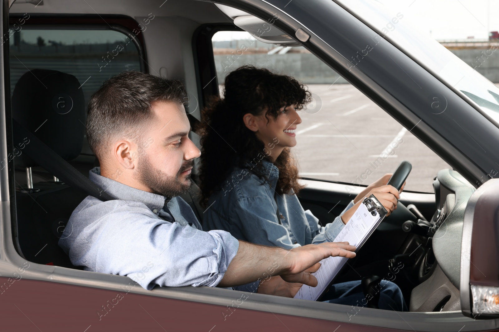 Photo of Driving school. Happy student passing driving test with examiner in car at parking lot