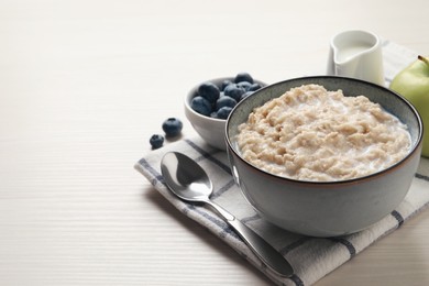 Photo of Tasty oatmeal porridge served on light wooden table, space for text