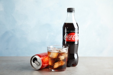 MYKOLAIV, UKRAINE - NOVEMBER 15, 2018: Bottle, glass and can with Coca Cola on table against color background