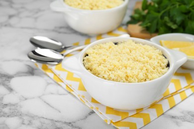 Photo of Bowl of tasty couscous on white marble table, closeup. Space for text