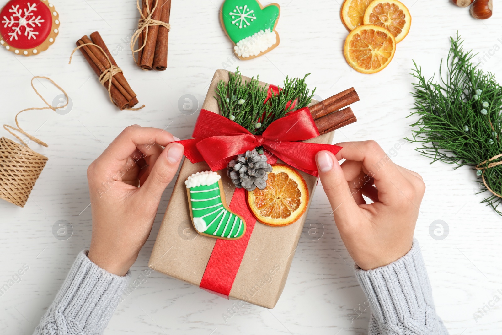 Photo of Woman wrapping Christmas gift at white wooden table, top view