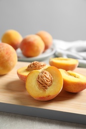 Wooden board with fresh sweet peaches on table, closeup