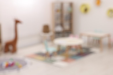 Stylish kindergarten interior with toys and modern furniture, blurred view