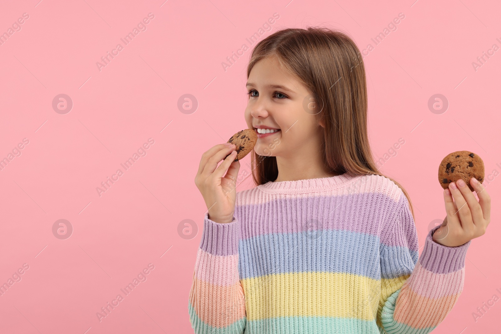 Photo of Cute girl with chocolate chip cookies on pink background. Space for text