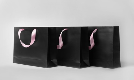 Photo of Paper shopping bags with ribbon handles on white background. Mockup for design