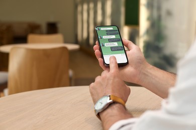 Man texting via mobile phone indoors, closeup. Device screen with messages