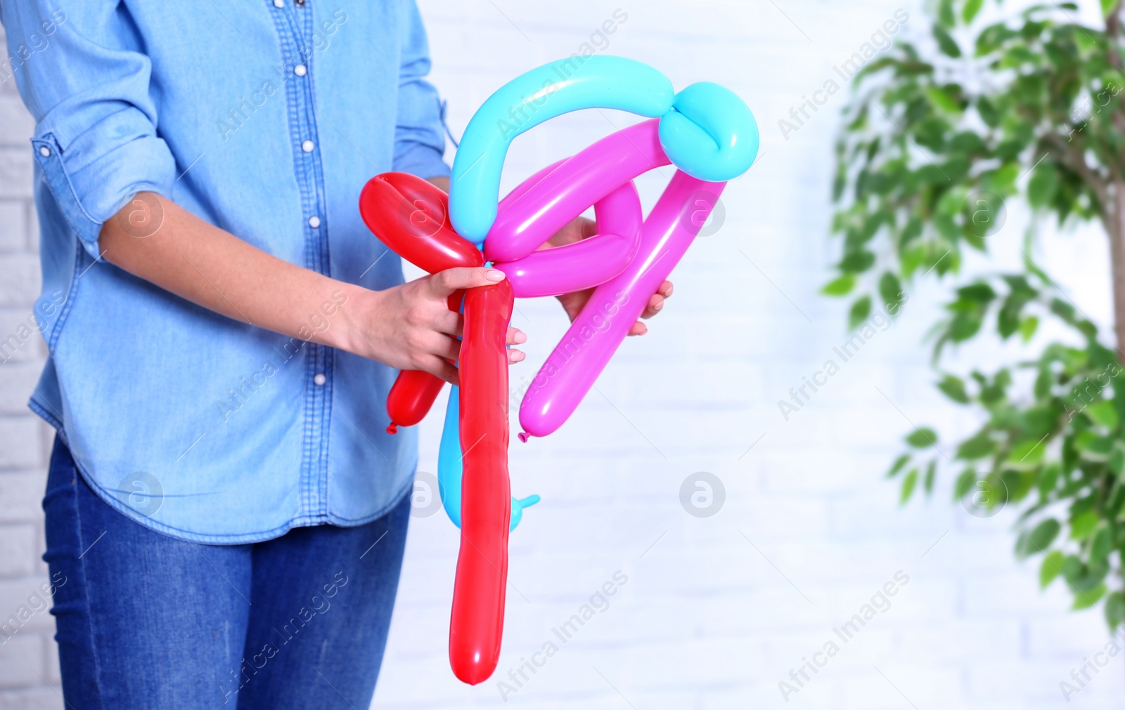 Photo of Woman making balloon figure on blurred background, closeup. Space for text