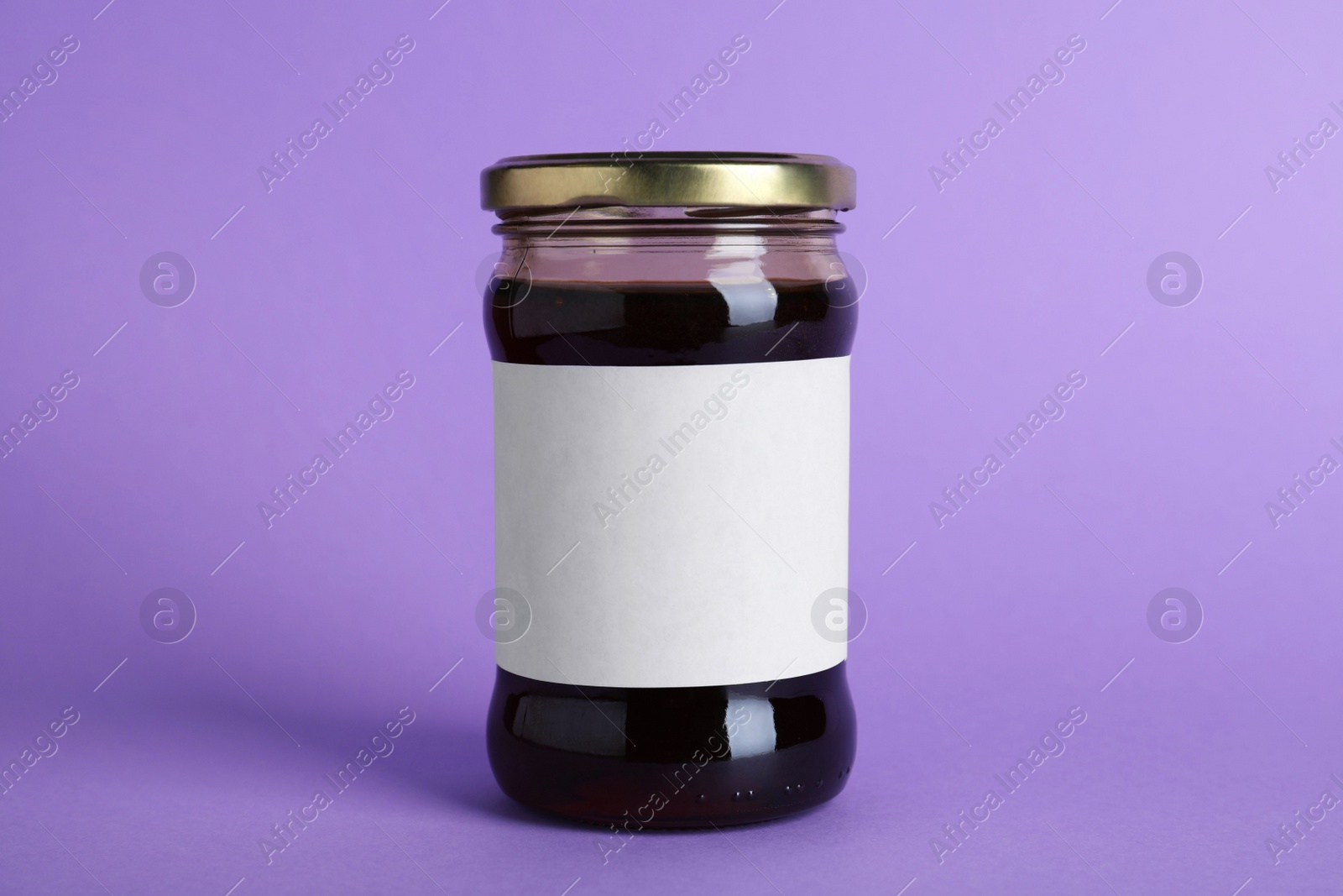 Photo of Jar of organic honey with blank label on violet background. Space for text