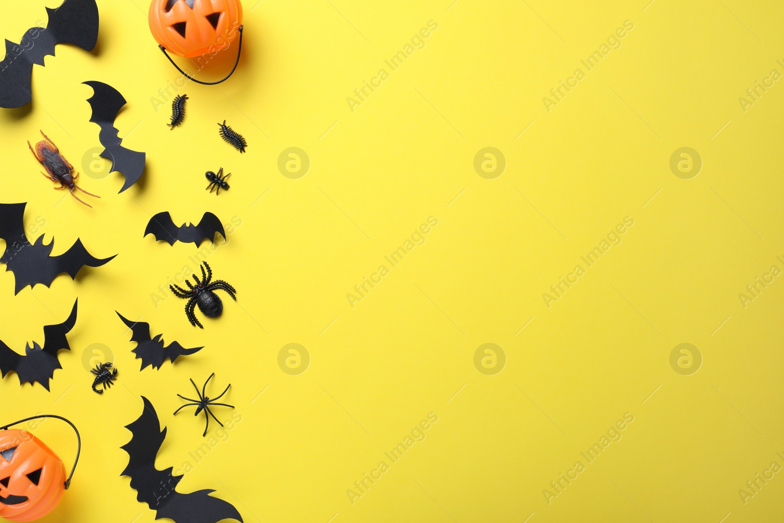 Photo of Halloween decor elements on yellow background, flat lay. Space for text