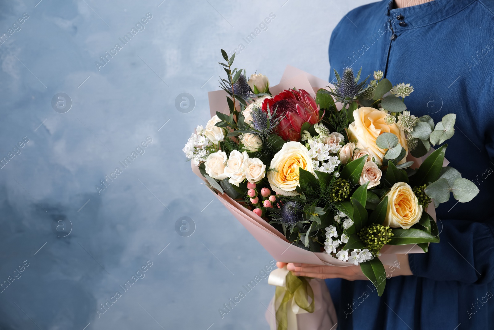 Photo of Woman with bouquet of beautiful roses on light blue background, closeup. Space for text