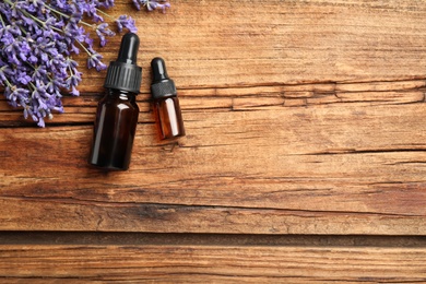 Flat lay composition with lavender flowers and essential oil on wooden background. Space for text