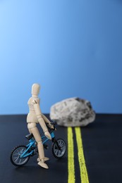 Photo of Overcoming barries for development and success. Wooden human figure with toy bicycle can't move forward due to stone blocking way, space for text