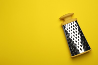 Photo of Modern grater on yellow background, top view. Space for text