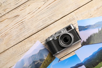 Photo of Vintage photo camera and beautiful printed pictures on wooden table, flat lay with space for text. Creative hobby