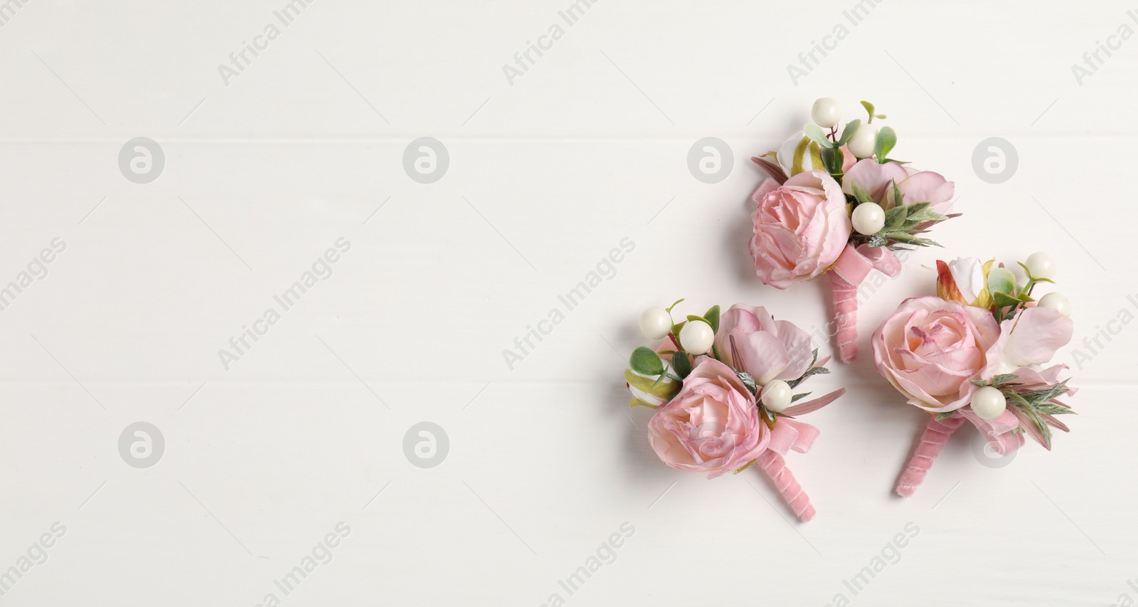 Photo of Beautiful boutonnieres on white background, flat lay. Space for text