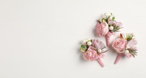 Beautiful boutonnieres on white background, flat lay. Space for text