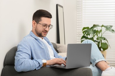 Photo of Man using laptop on couch at home