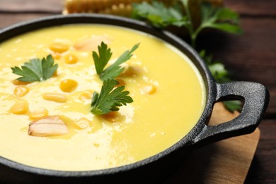 Photo of Delicious creamy corn soup on wooden table, closeup