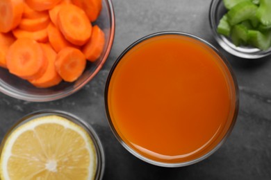 Photo of Tasty carrot juice and ingredients on black marble table, flat lay