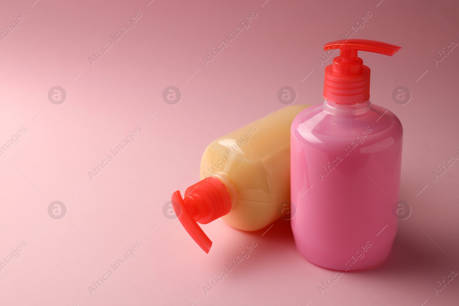 Photo of Bottles of liquid soap on pink background. Space for text