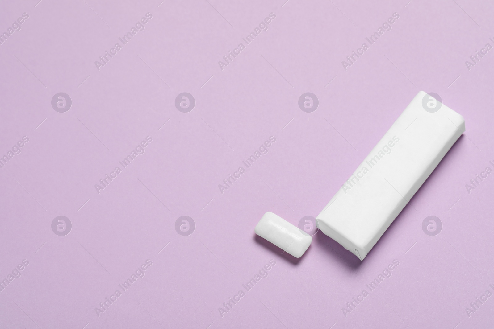 Photo of Pack of tasty chewing gums on lilac background, above view. Space for text