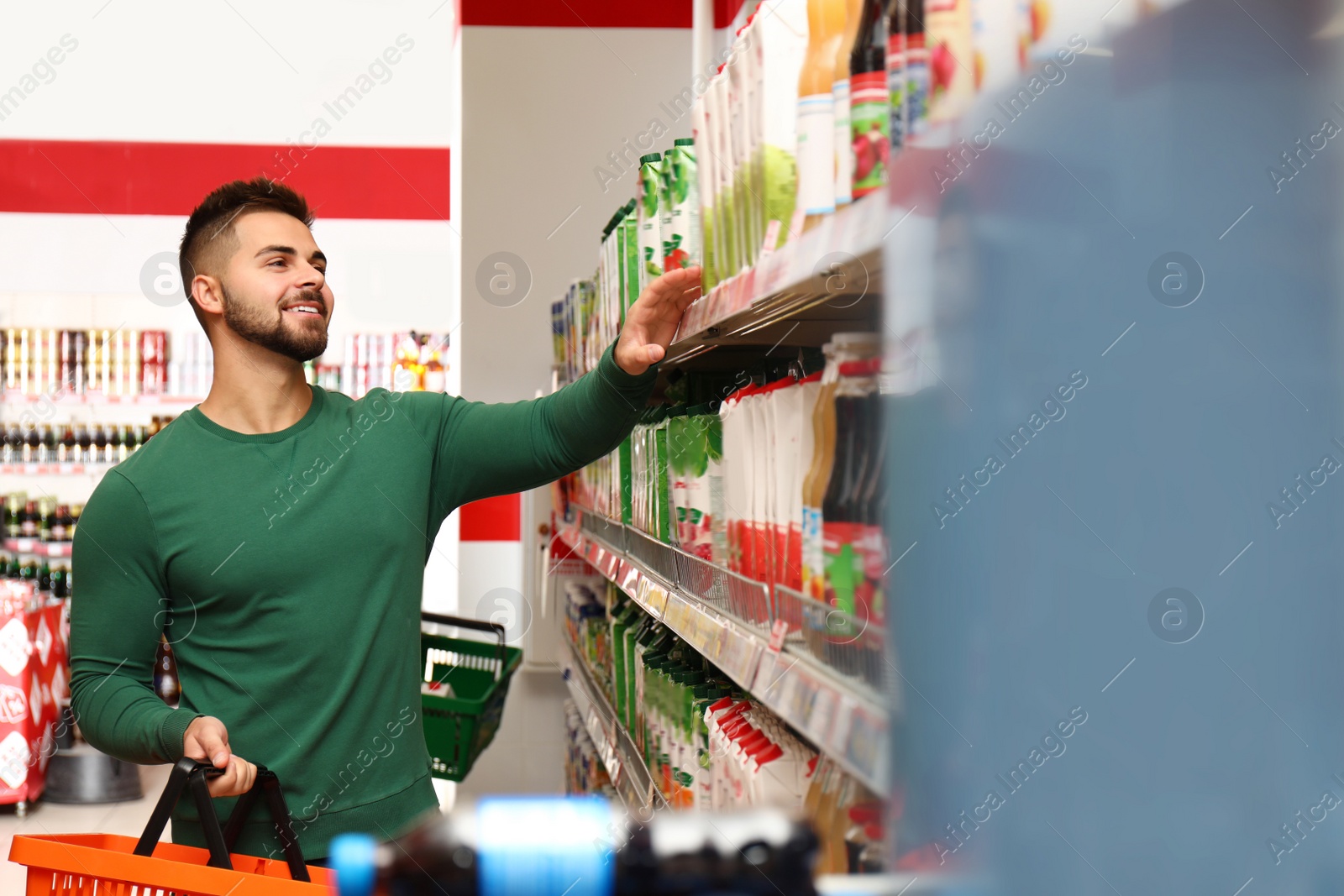Photo of Young man with shopping basket in supermarket