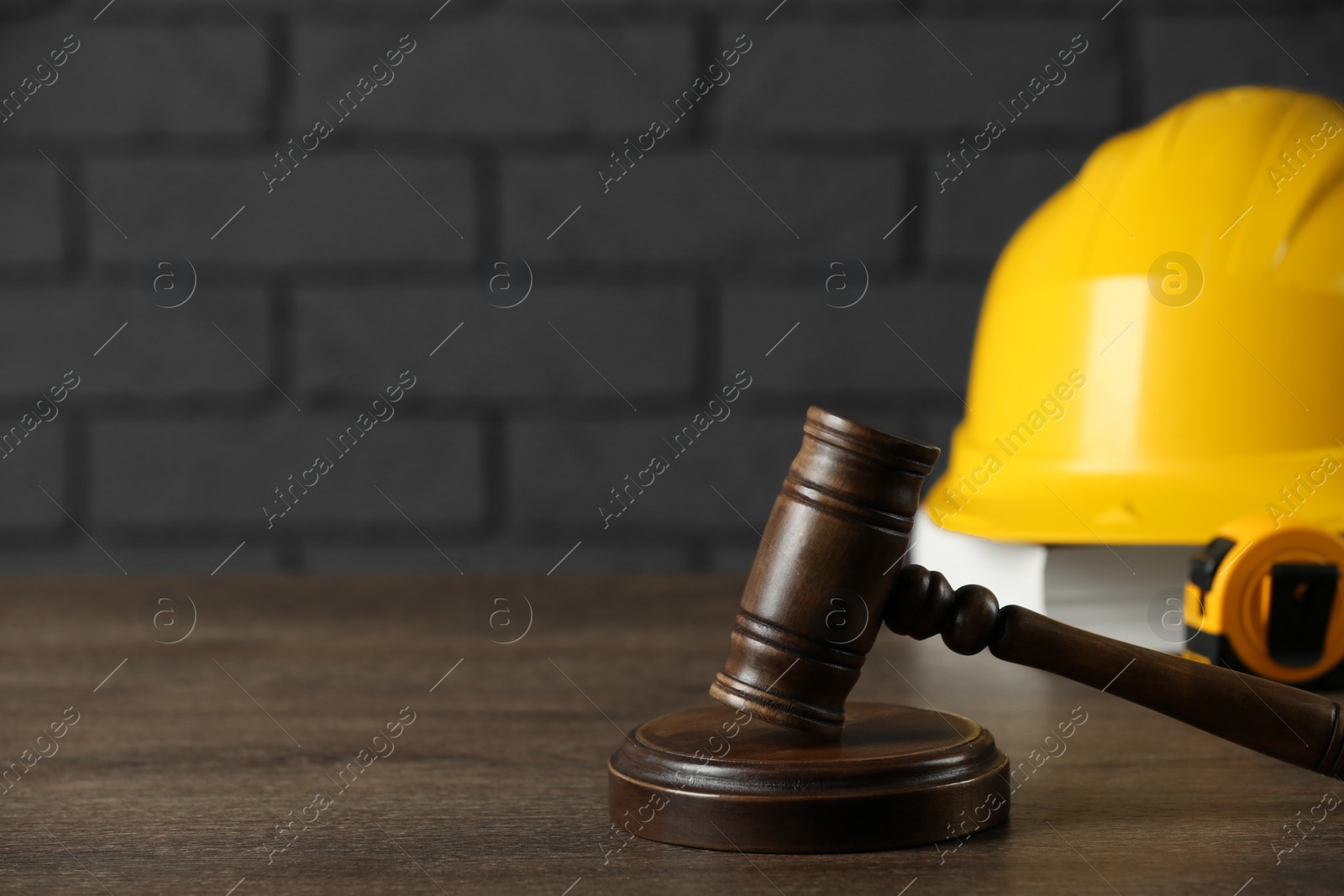 Photo of Construction and land law concepts. Gavel, hard hat, measuring tape and book on wooden table, space for text