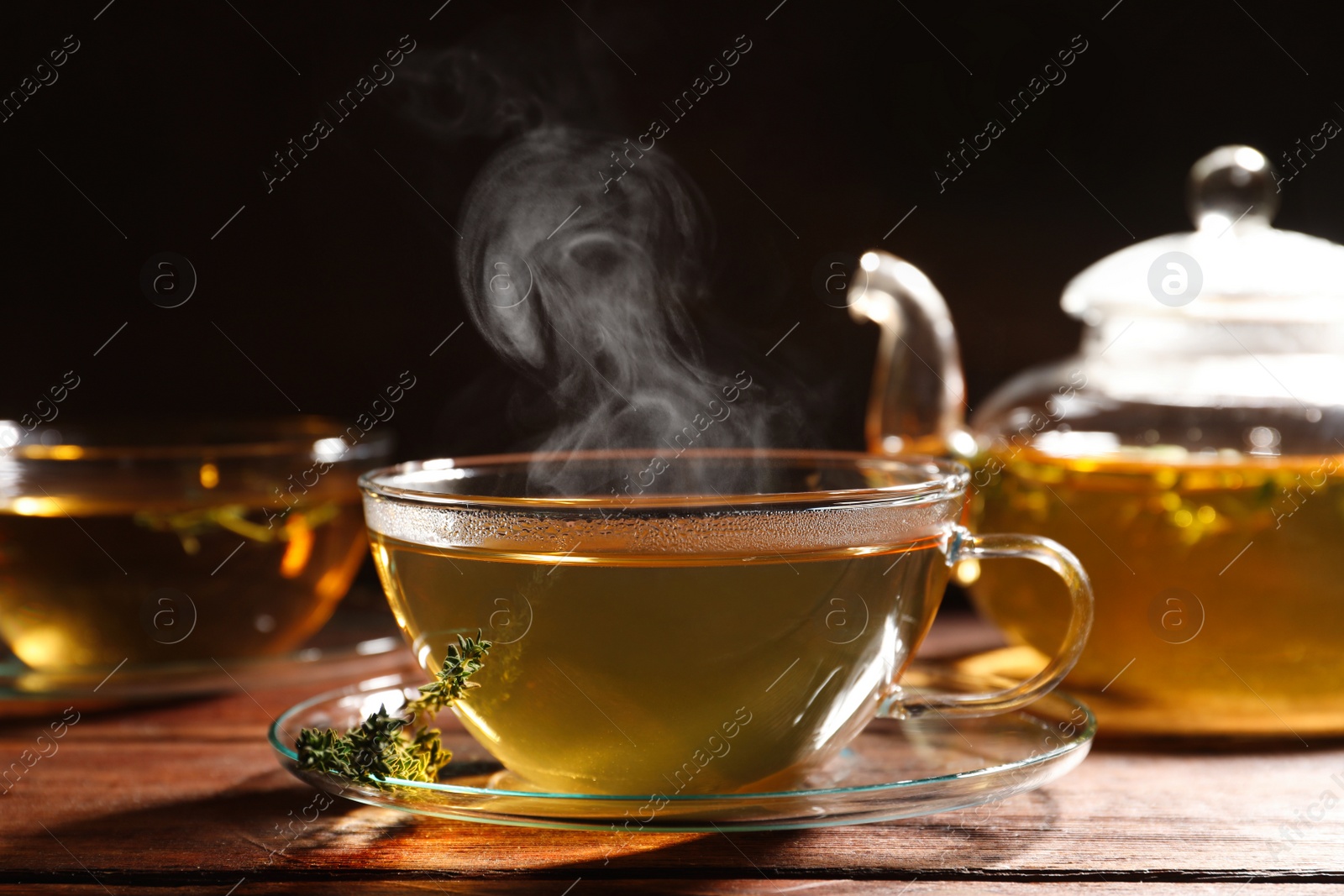 Photo of Cup of aromatic herbal tea and thyme on wooden table