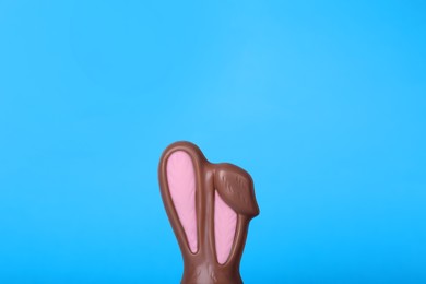 Chocolate bunny ears on light blue background, closeup with space for text. Easter celebration