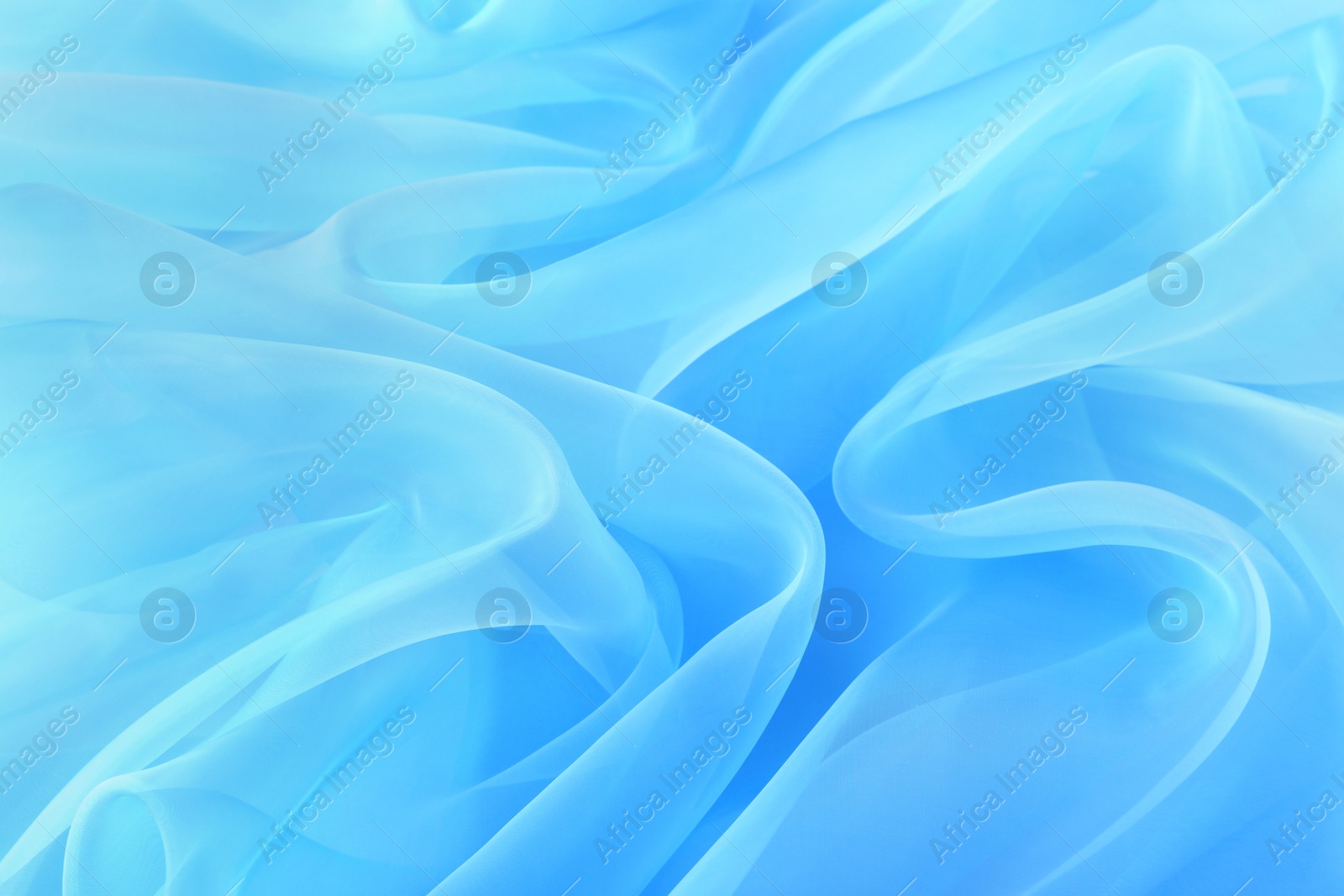 Photo of Beautiful light blue tulle fabric as background, closeup