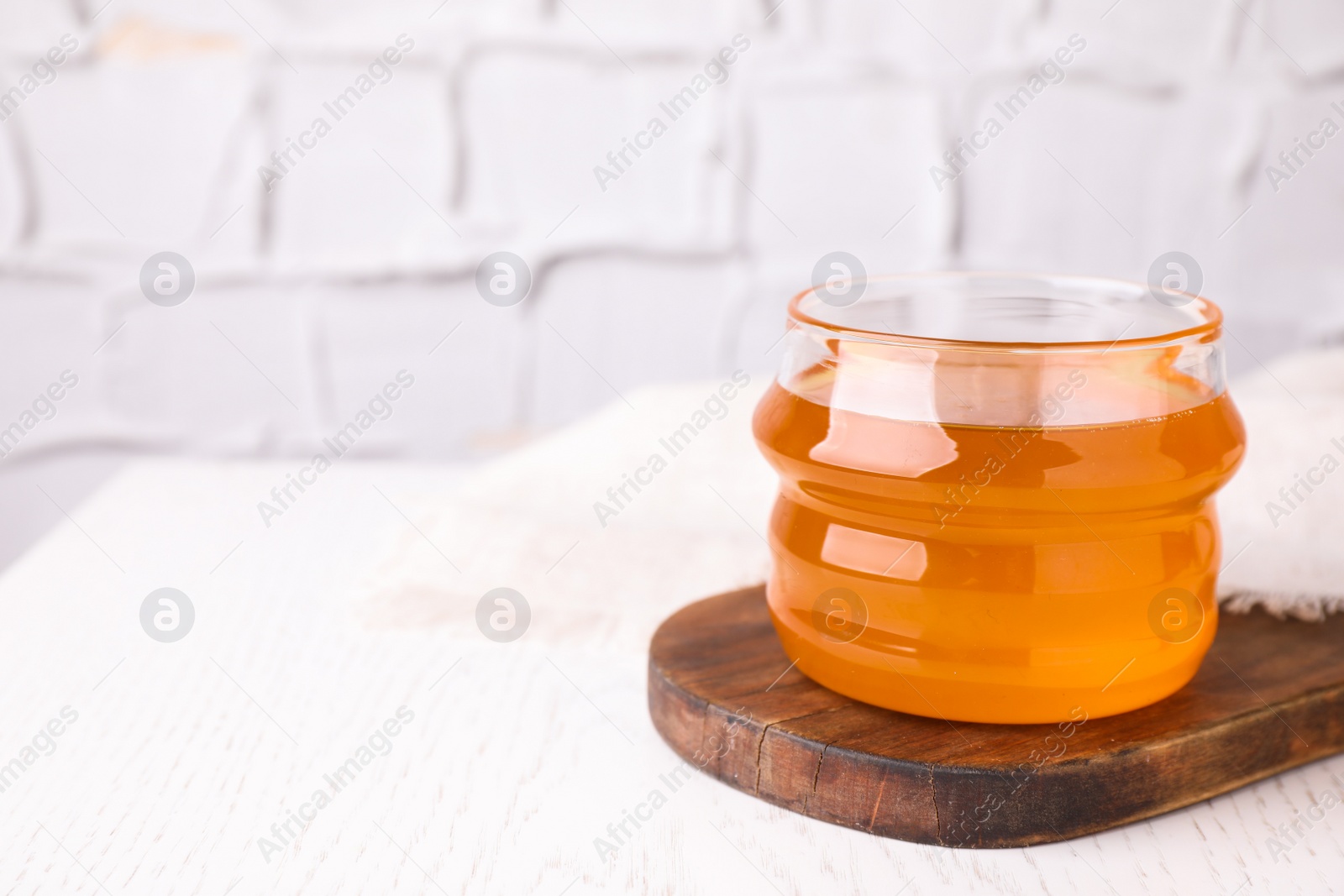 Photo of Tasty aromatic honey on white wooden table. Space for text