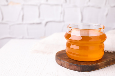 Tasty aromatic honey on white wooden table. Space for text