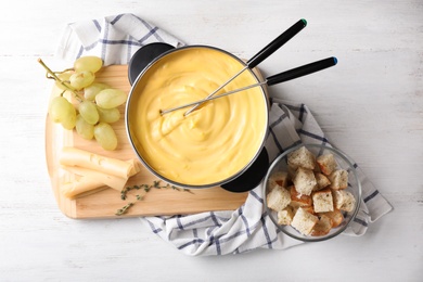 Photo of Flat lay composition with pot of delicious cheese fondue on wooden table