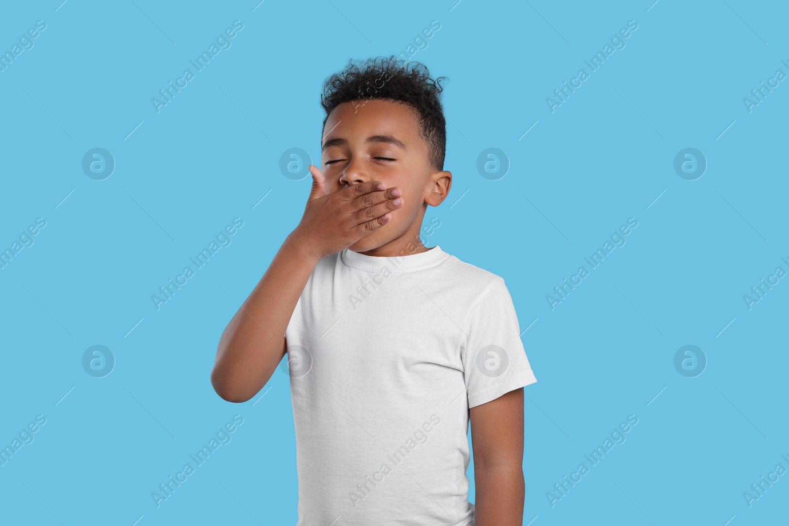 Photo of Boy yawning on light blue background. Insomnia problem