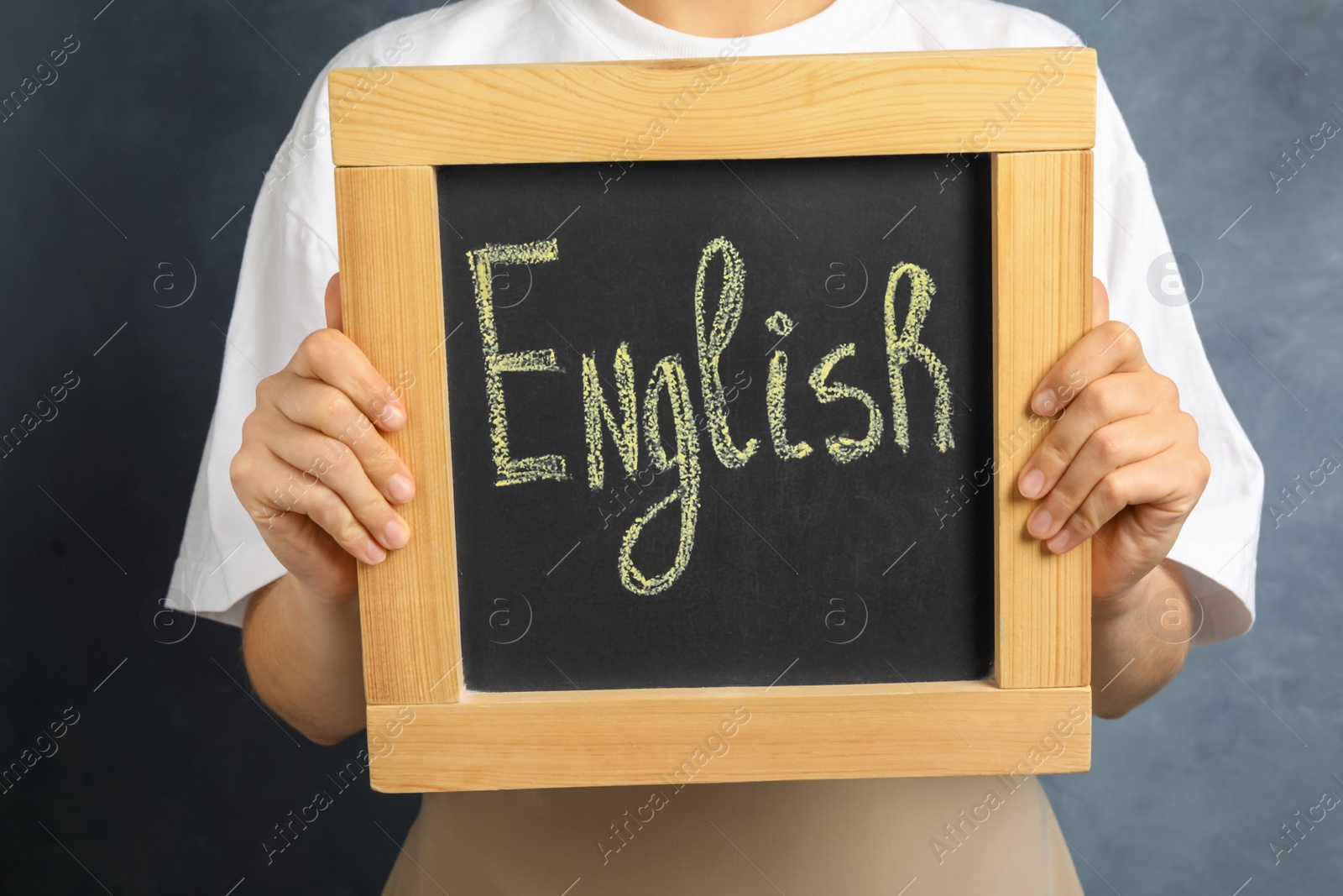 Photo of Woman holding board with word English on grey background, closeup