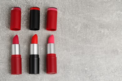 Different lipsticks on grey table, flat lay. Space for text